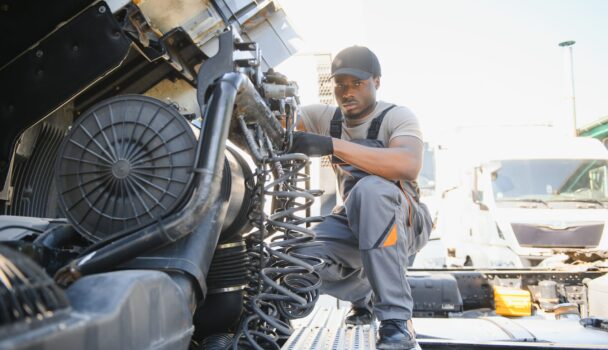 African american Professional Truck Mechanic Rebuilding Heavy Duty Truck Diesel Engine. Automotive Industry Theme.