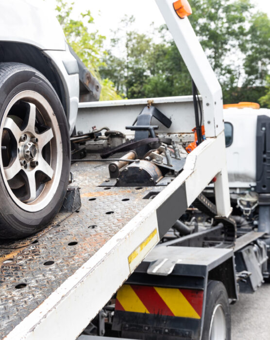 Cable attached to broken down car being pulled onto flatbed tow truck