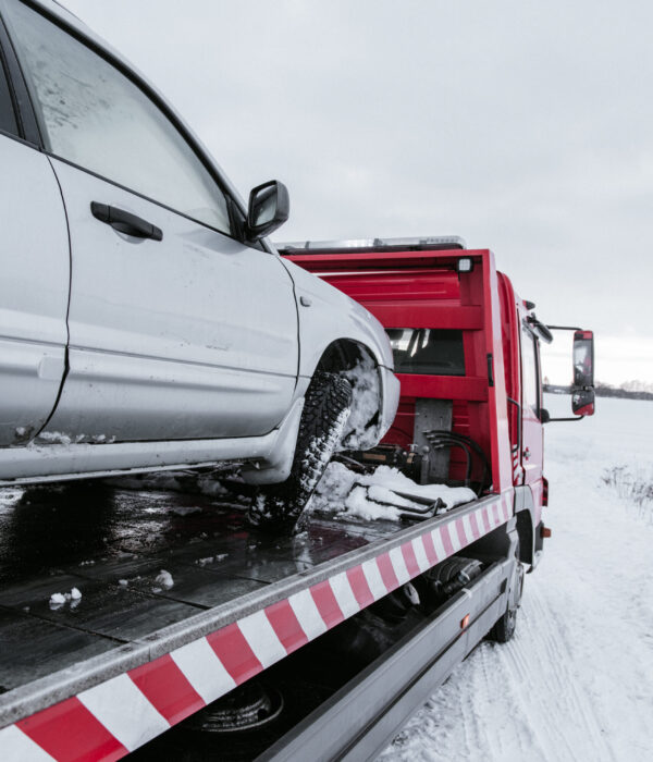 Broken automobile on breakdown truck on snow meadow in Vilnius, Lithuania