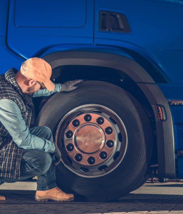 Caucasian Driver Checking Semi Truck Wheels Looking For Potential Issues. Transportation Industry Safety.